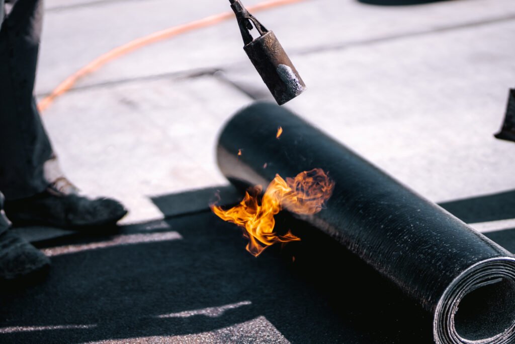 Waterproofing rooftop, waterproof insulation with bituminous membrane system. Professional workers waterproofing house construction site.